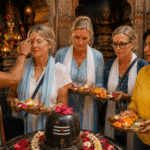 A Hindu priest applying a traditional red tilak blessing onto the forehead of international tourists holding prayer offerings during a personalized Delhi Temple tour with a local guide.