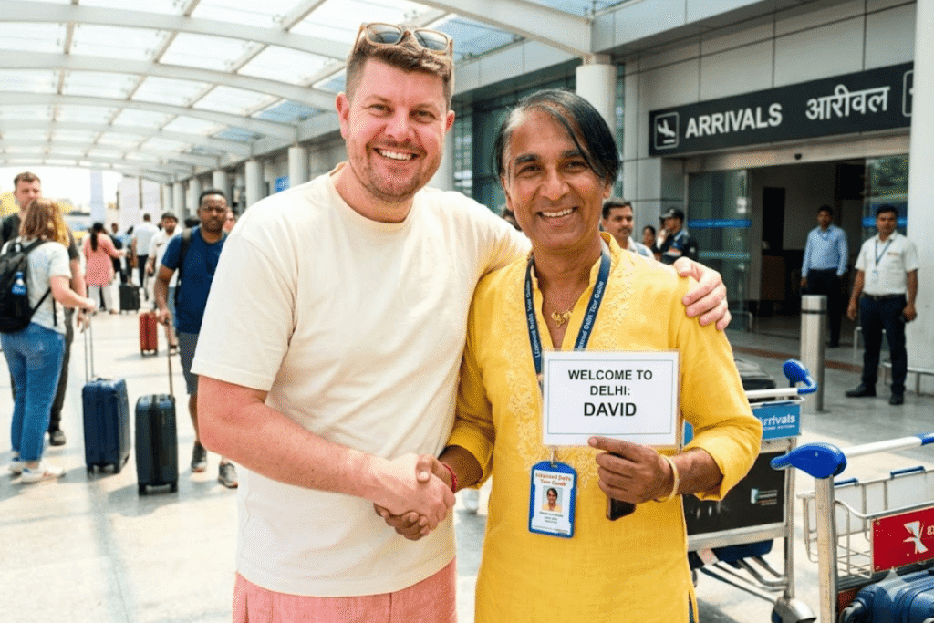 Licensed Delhi tour guide Harry (in yellow kurta) welcomes a smiling David from London at the Delhi airport terminal