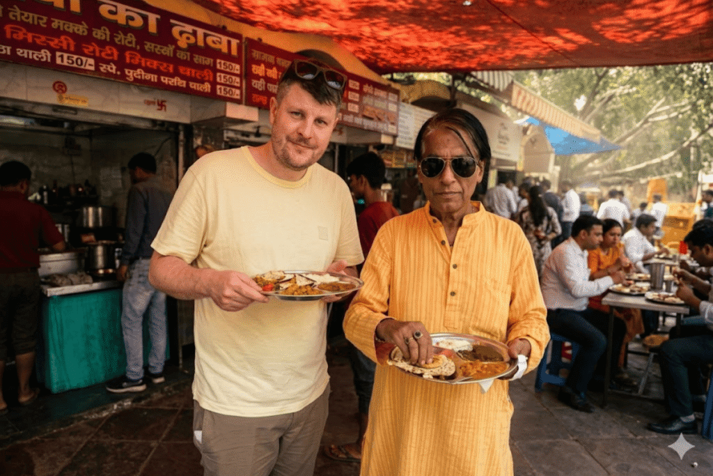 International tourist David and Delhi tour guide Harry holding traditional steel plates of authentic Indian street food at a local dhaba restaurant