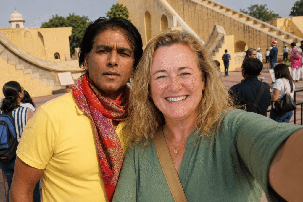 Harry and Kath are at Jantar Mantar Jaipur there are local and foreign tourists in the scene and Kath is smiling taking selfie with Tour Guide in Jaipur Harry and the big sun dial