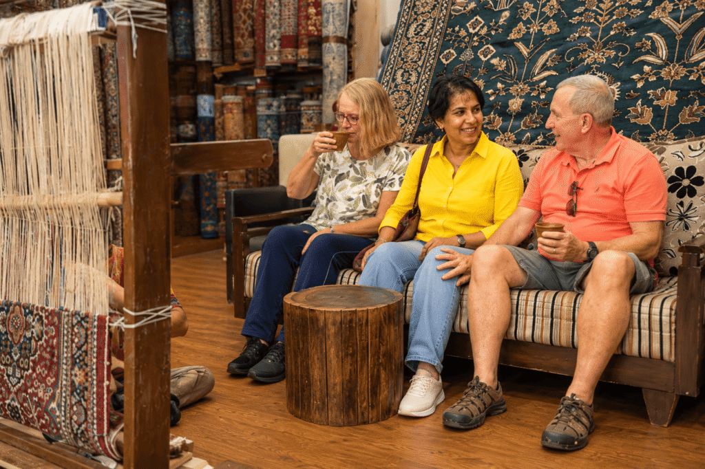 Tourists watching a traditional Kashmiri carpet weaving demonstration during a private Delhi Shopping Tour.